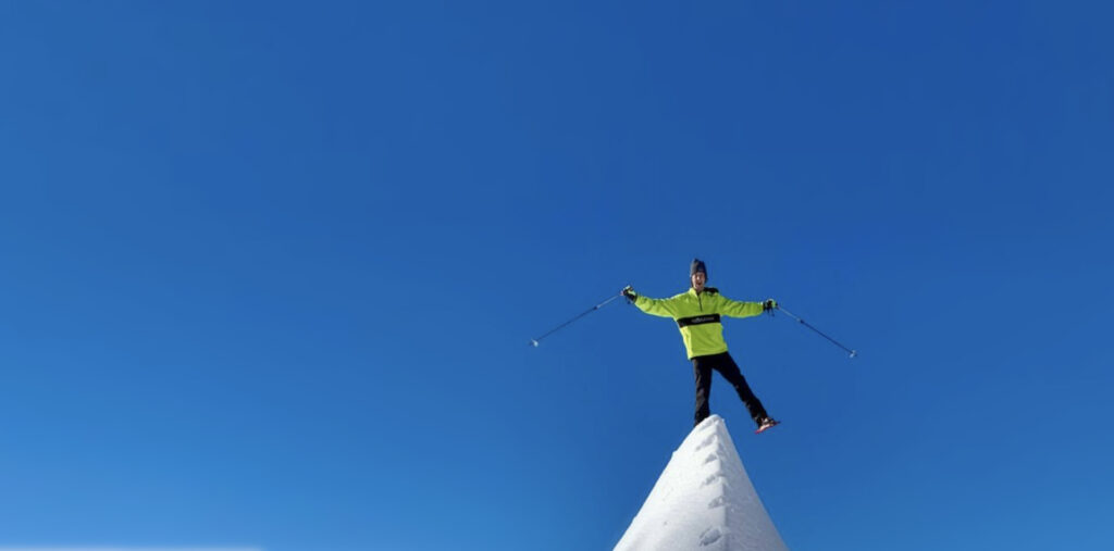 A man wearing snowshoes while balancing on the spine of a winter mountain