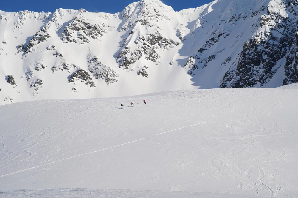 A group of three hikers traversing a snowy mountainside