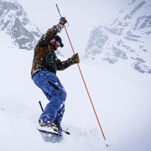 A man wearing snowshoes while testing for avalanches in the mountains
