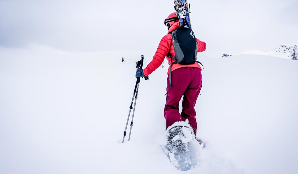A backcountry skier hiking up a snowy hill wearing Snowfoot Classic snowshoes