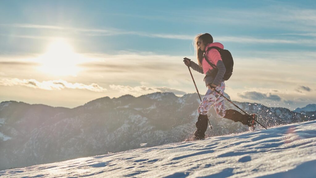 a woman running down a slushy mountain side in snowshoes