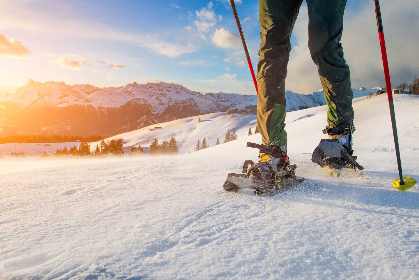 snowshoer on corn snow in the mountains with a sunset backdrop