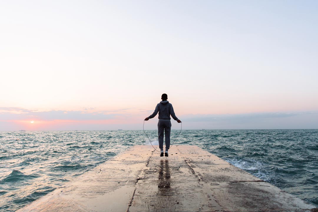 a person jump roping on a dock in the middle of Lake Superior in order to exercise during the summer