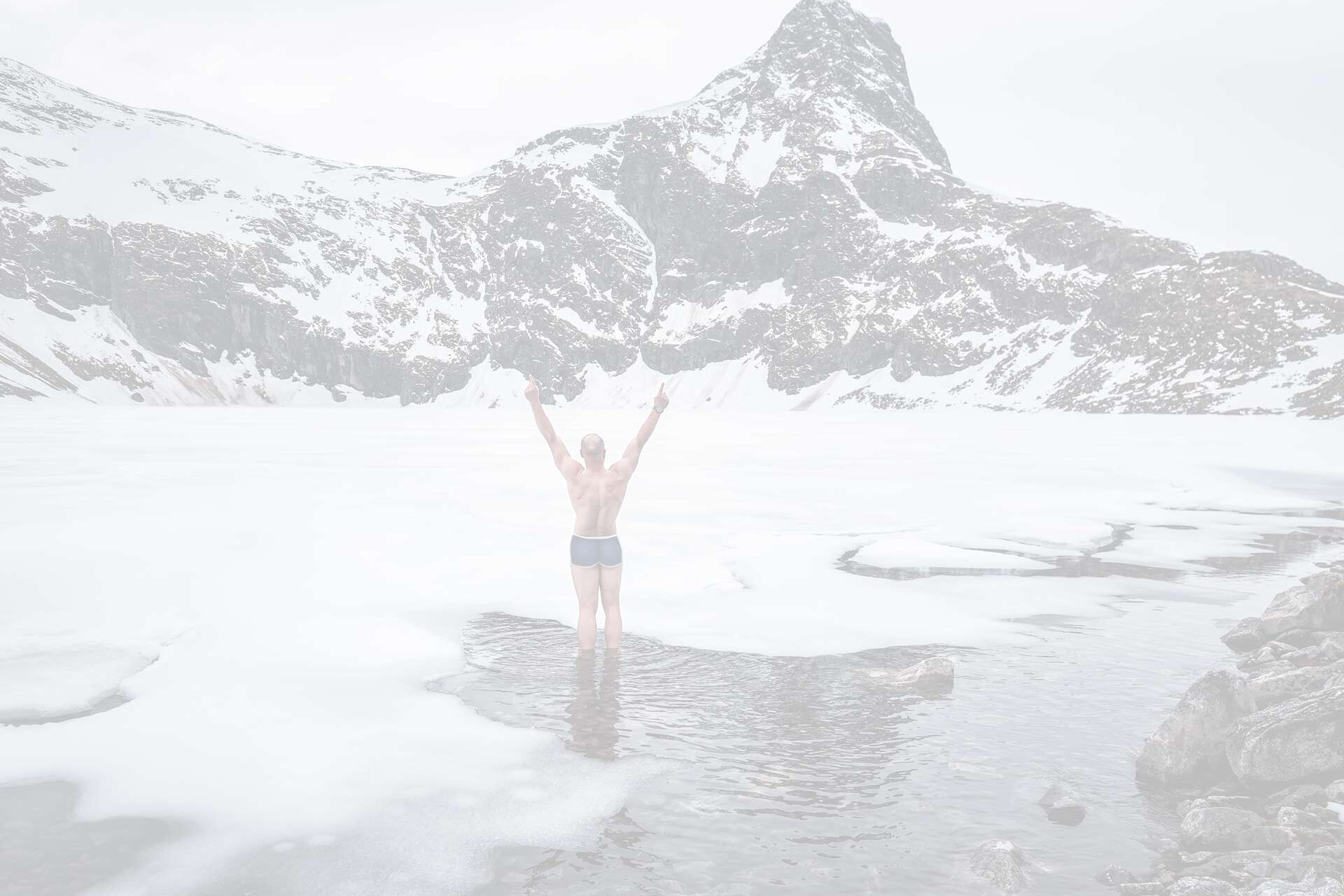 A man standing in the middle of a frozen mountainside lake for natural therapy during winter