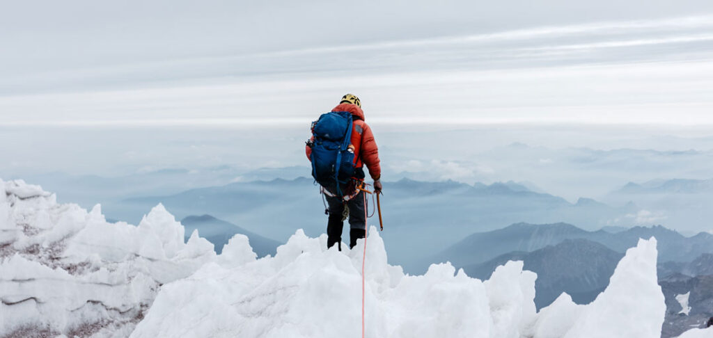 Man standing on top of a mountain peak in Mount Rainier National Park